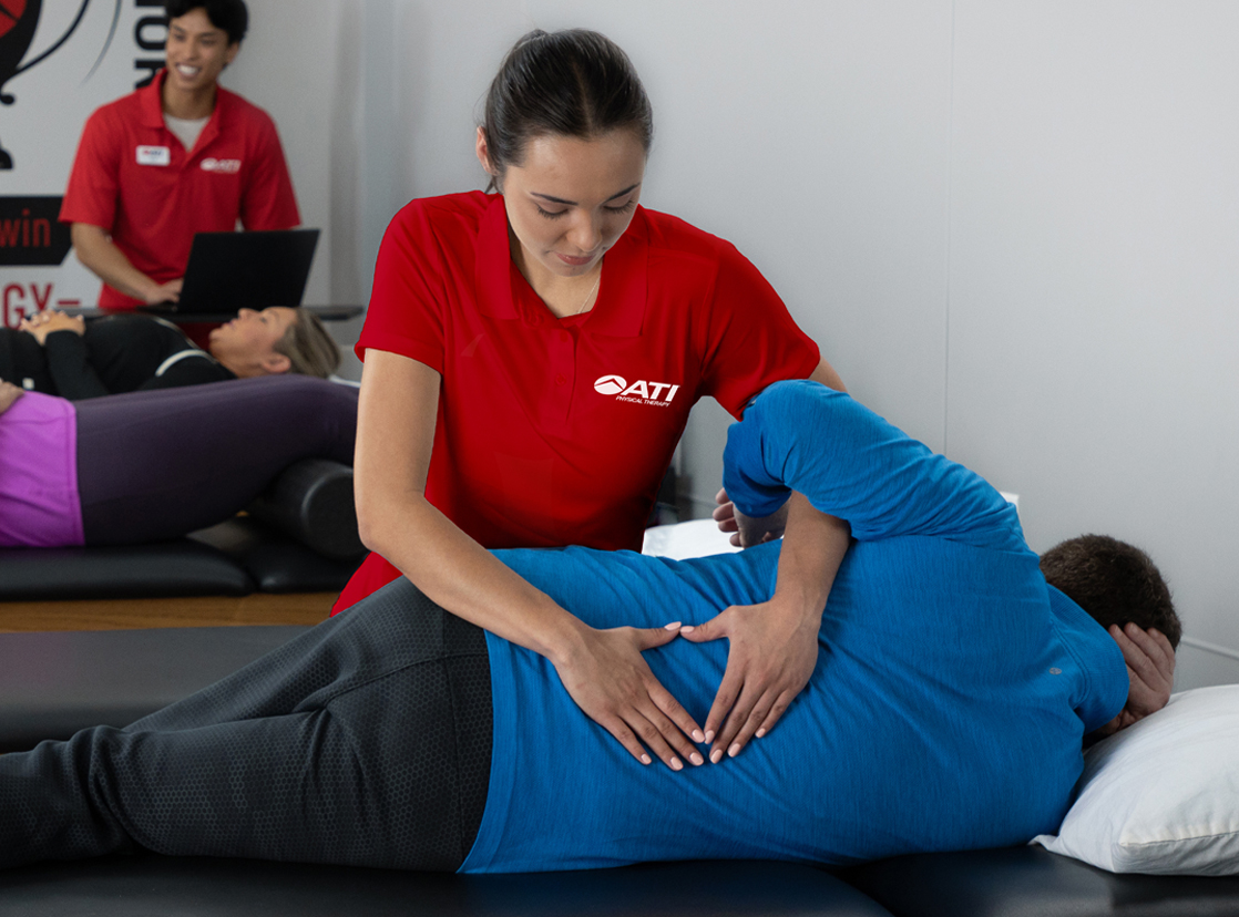 ATI therapist assisting a patient with back pain